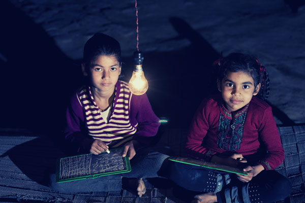 Image of two girls staring at a light bulb above them.