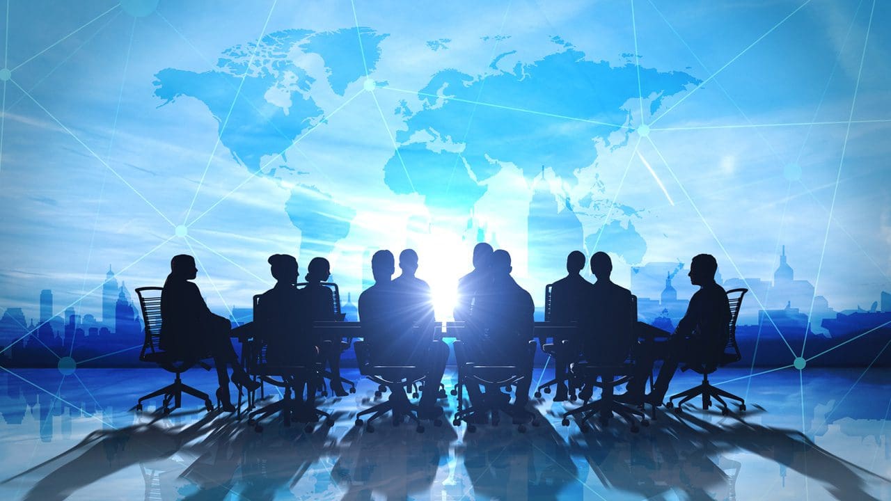 Silhouette image of people at a conference table, juxtaposed against a world map.