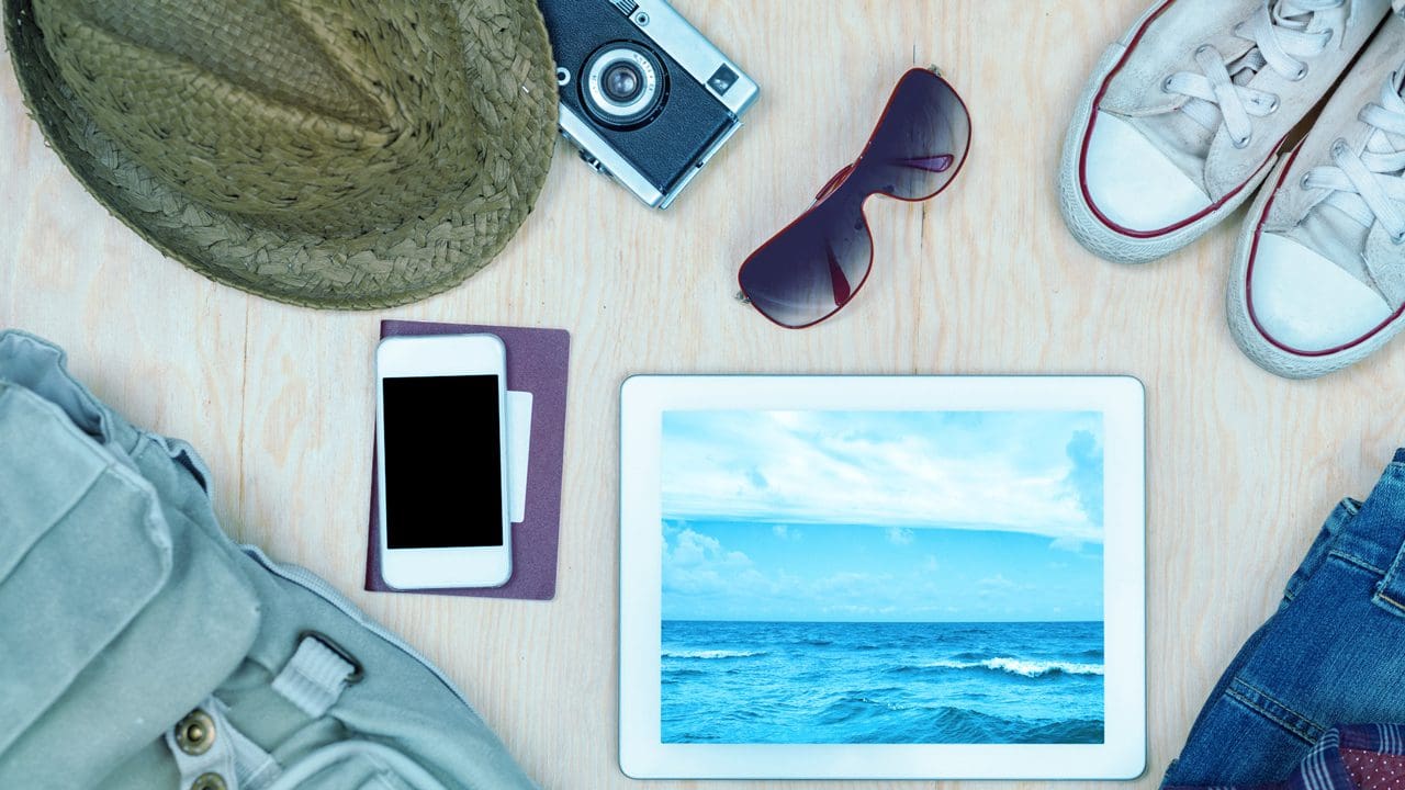 Items used during summer vacation, such as a hat, shoes, camera, sunglasses, phone, tablet, and clothing.
