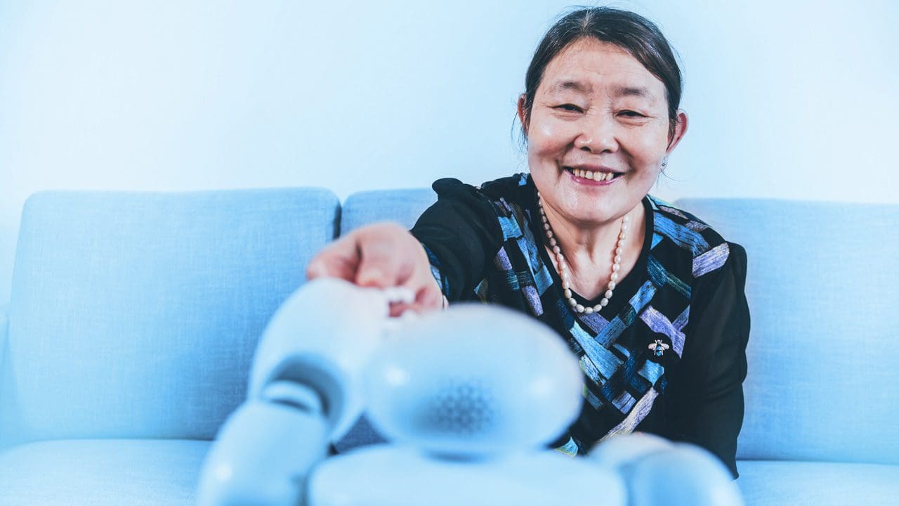 Elderly lady touching a robot's hand