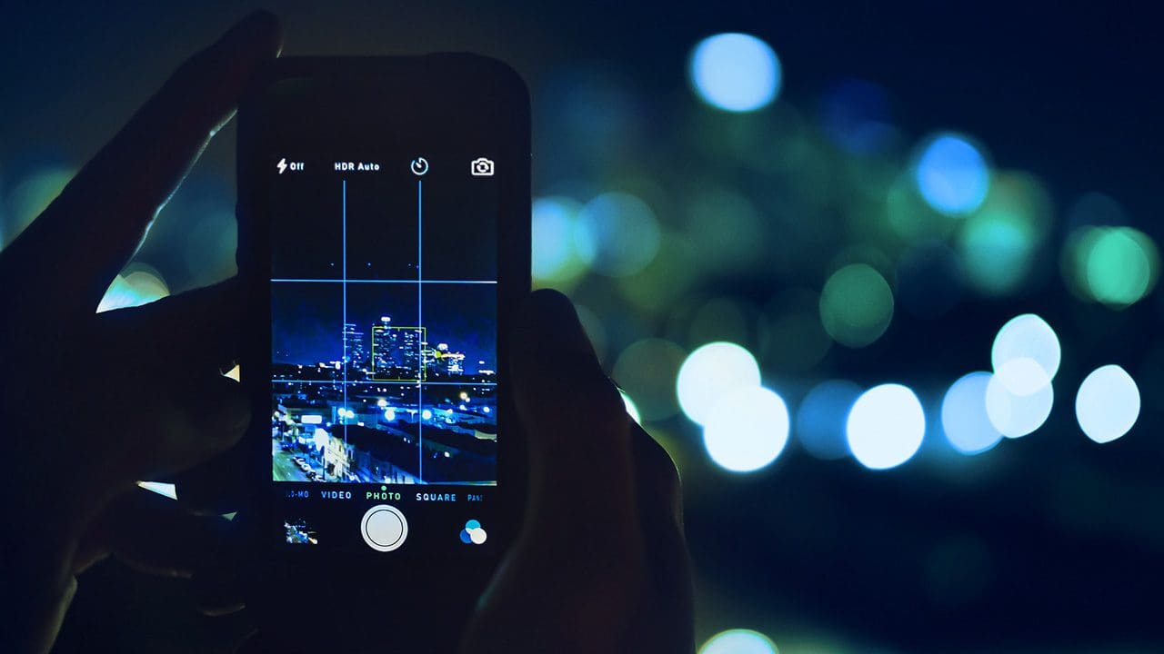 Image of a person using an iPhone to take a landscape picture at night.