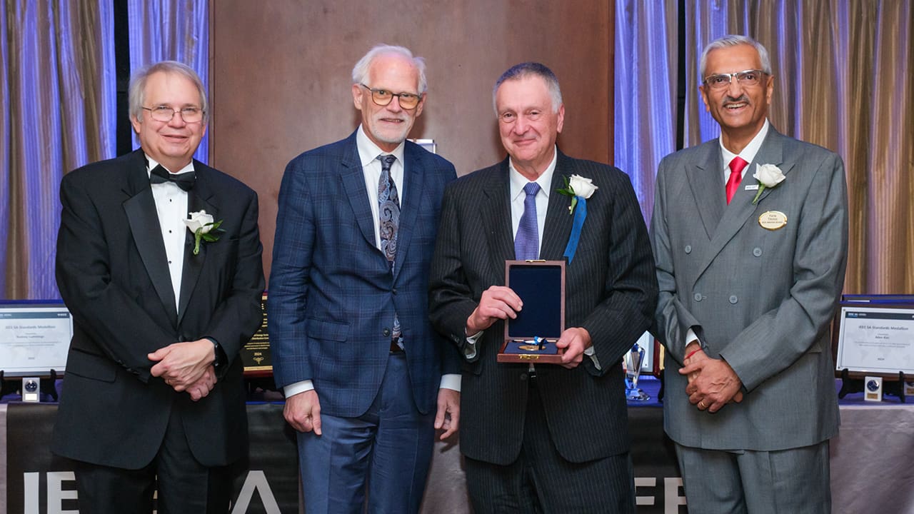 IEEE SA President Jim Matthews, IEEE President Tom Coughlin, and Yatin Trivedi posing for a photo with an IEEE SA Awards honoree.